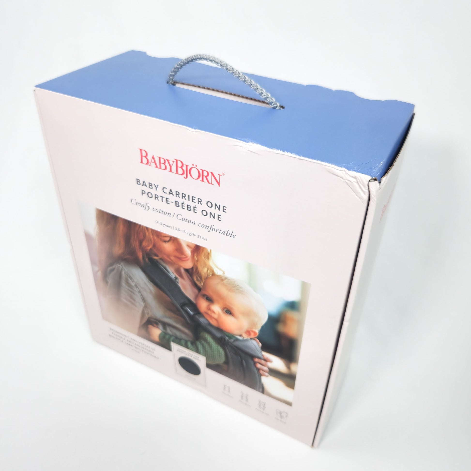 Packaging box for BABYBJÖRN Baby Carrier One in Black Cotton with image of a mother holding a baby and the carrier itself.
